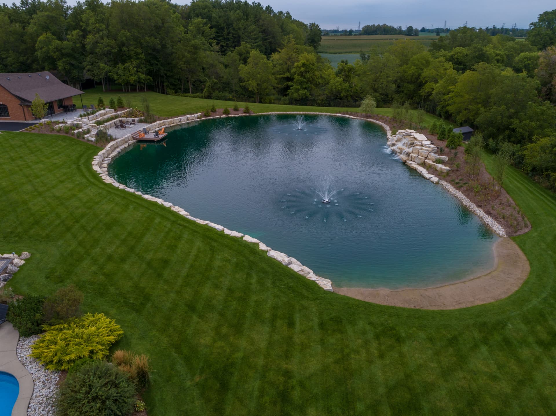 Armour stone pond with aerating fountains and a sand beach entry