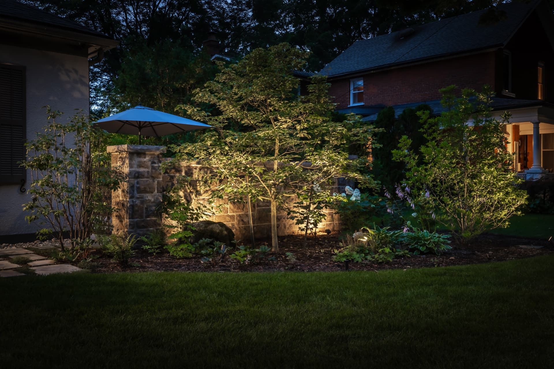 Garden beds and stone walls illuminated by uplighting