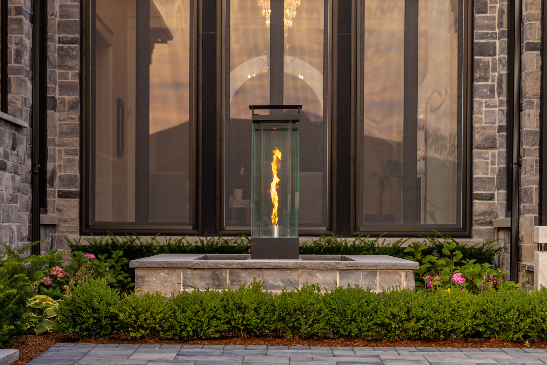 Glass fire tower set in a stone courtyard planter
