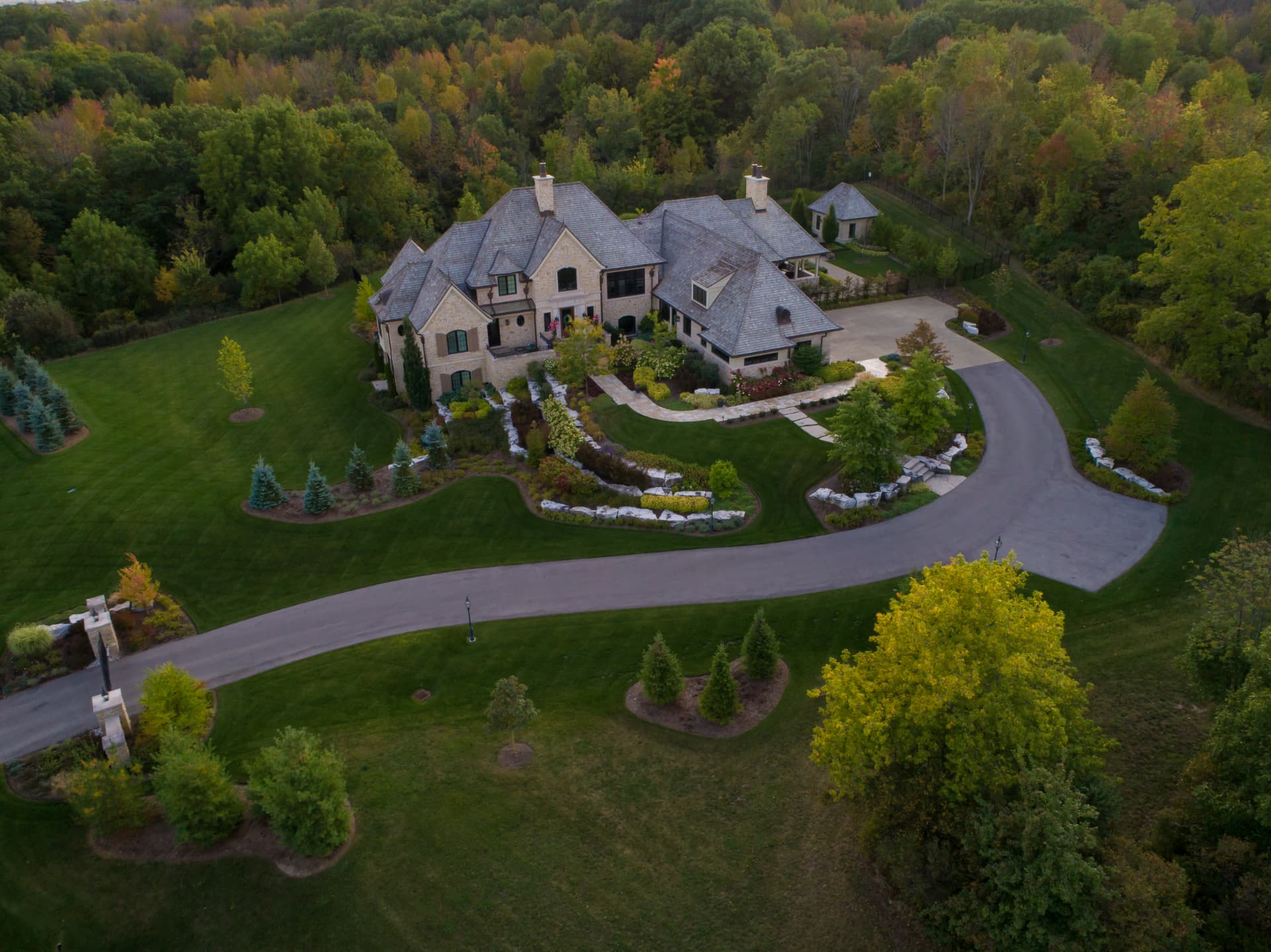 Aerial view of a manicured estate with winding drive and curated gardens