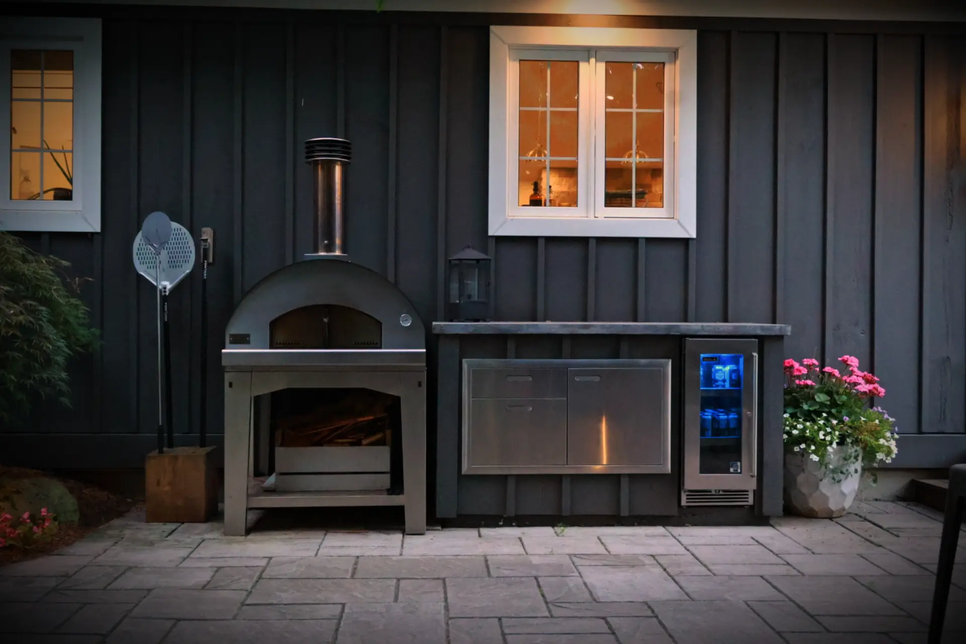 Wood-fired pizza oven with stainless storage cabinet and beverage fridge