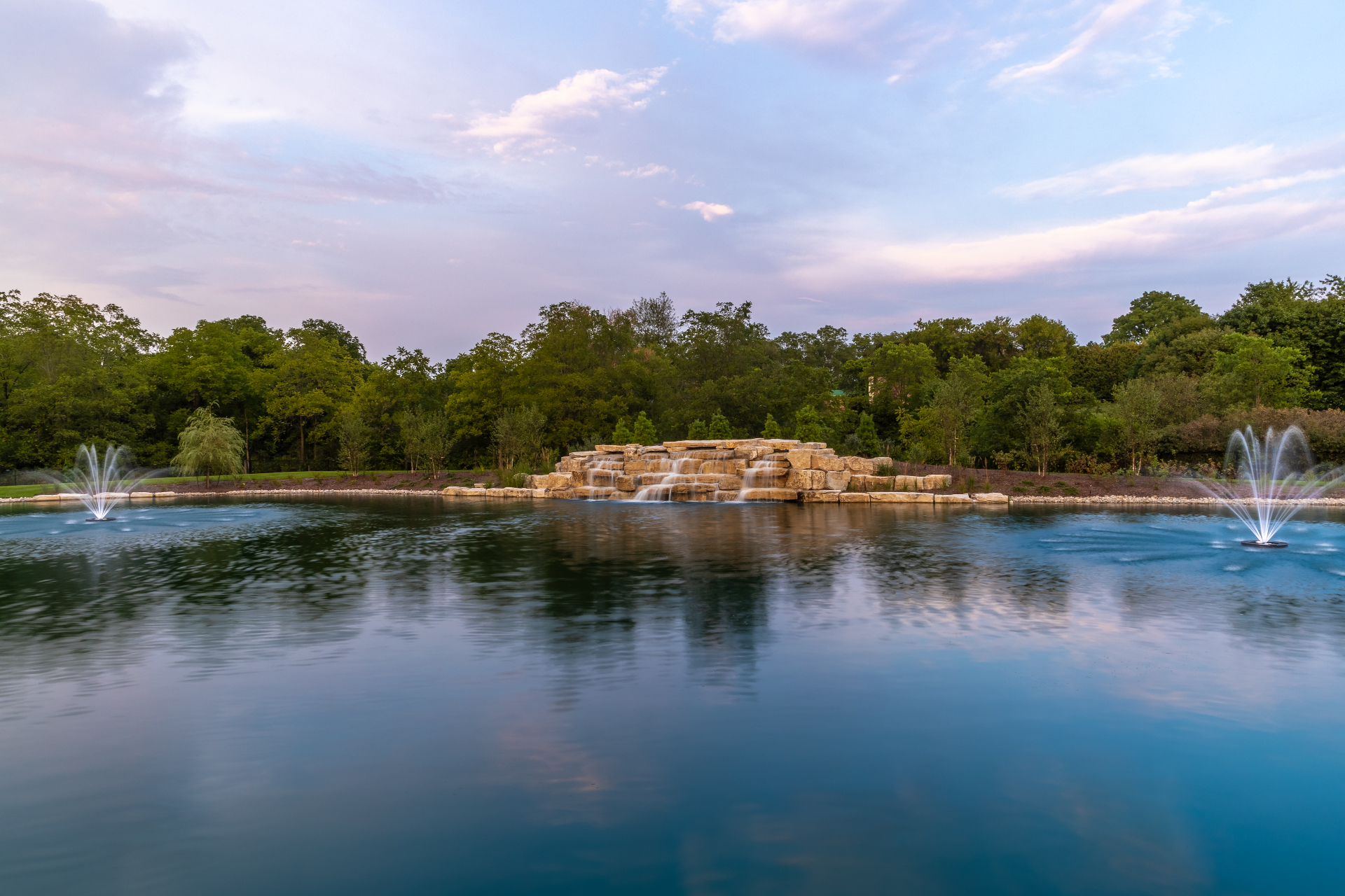 Natural stone cascade with floating fountains at dusk
